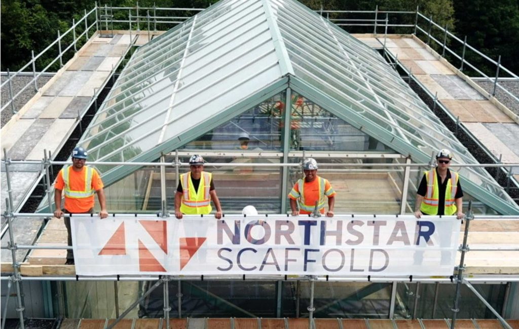 Northstar Access scaffold crew posing with company banner on top of scaffold build
